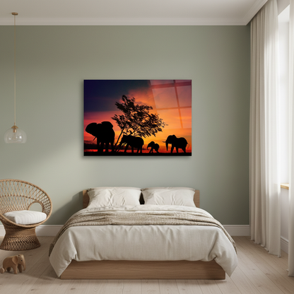 Horizontal glass wall art featuring a family of elephants at sunset displayed in a sage green safari children’s bedroom